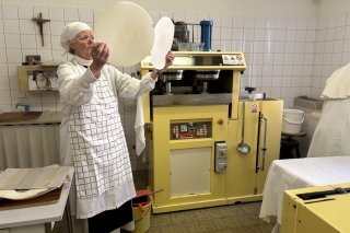 Chaque détail a son importance : ici Sœur Marie-Raphaële vérifie la qualité des galettes juste après la cuisson. Derrière elle, la machine qui sert à faire le pétrin et cuire la pâte.