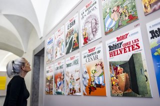 Une personne regarde des reproductions des albums d'Asterix lors d'une visite de presse de la nouvelle exposition Asterix le mercredi 2 avril 2025 au Chateau de Saint-Maurice. (KEYSTONE/Jean-Christophe Bott)