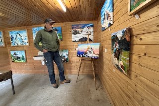 André Georges dans la grange où sont exposés ses tableaux : sur le chevalet, le Cervin