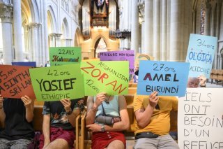 Sur la rangée de droite, les militants et sympathisants tenaient chacun des pancartes colorées avec le nom, l'âge et le pays d'origine de requérants d'asile déboutés et menacés de renvoi.